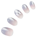 Five almond-shaped press-on nails with a soft pink-to-silver gradient and fine glitter, arranged diagonally on a white background. One nail features a white bow design with a small rhinestone accent.
