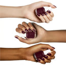 Three hands with dark nail polish holding a bottle of Essie nail polish.