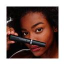 Woman holding a black cosmetic product labeled 'Telescopic Lift' close to her face.