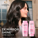 L'Oreal Paris Elvive shampoo bottles with a woman with long hair in the background