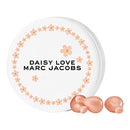 A round tin with 'Daisy Love Marc Jacobs' written on it, adorned with a floral pattern, alongside two capsules of the fragrance.