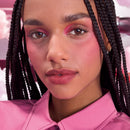 Woman with braided hair wearing a pink shirt against a pink background
