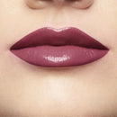 Close-up of a person wearing a glossy purple lipstick on a neutral background