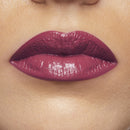 Close-up of a person's lips with glossy purple lipstick on a neutral background