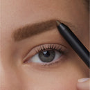 Eyebrow pencil being used on a person's eyebrow with a close-up of an eye.