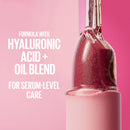 Pink skincare serum bottle with text about hyaluronic acid and oil blend on a pink background
