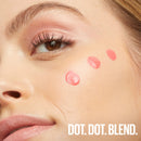 Close-up of a woman's face with makeup swatches on her cheek, featuring the text 'DOT. DOT. BLEND.'