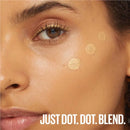 Close-up of a woman's face with makeup product dots and text 'JUST DOT. DOT. BLEND.'