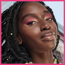Close-up of a woman with pink eye makeup and braided hair against a pink border.