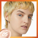 Close-up of a person with blonde hair and blue eyes, wearing an earring, on a white background.