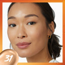 Close-up of a woman's face with a beige color swatch labeled '31' on an orange border.