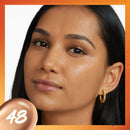 Close-up of a woman's face with a focus on skin texture, wearing gold hoop earrings.