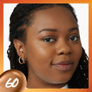 Close-up of a woman's face with a neutral expression, wearing gold hoop earrings.