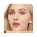 Close-up of a person with blonde hair and blue eyes, wearing earrings on a white background.