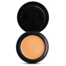 An open round makeup compact showing a smooth, solid pressed powder in a warm peachy-orange shade, set against a plain white background.