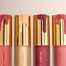 Four lipsticks with gold caps and different shades of pink on a light background.