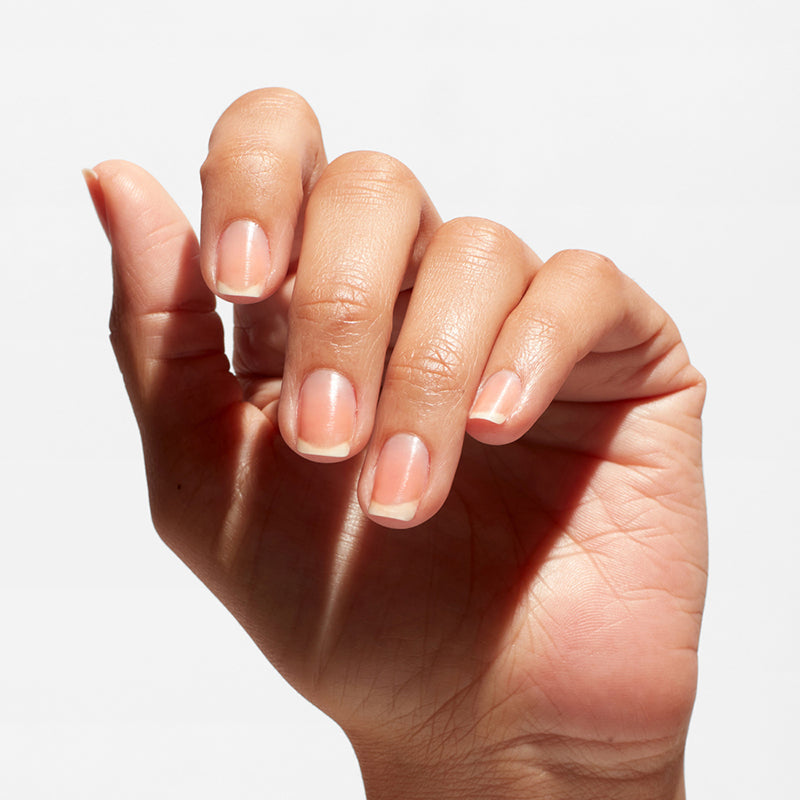 Close-up of a hand with light pink nail polish on a white background
