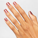 Hand with maroon nail polish on a light gray background