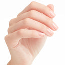 Close-up of a hand with soft, pastel pink nail polish on a white background