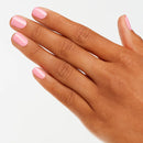 Hand with pink nail polish on a light gray background