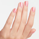 Hand with pink nail polish on a light gray background
