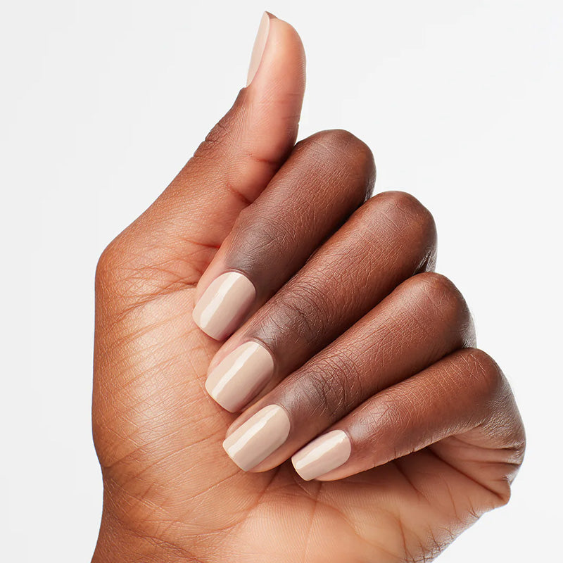Hand with beige nail polish on a light gray background