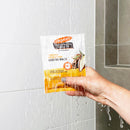 Hand holding a Palmer's hair care product under running water in a shower.