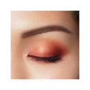 Close-up of a woman's eye with orange eyeshadow and a white background