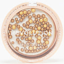 Revolution makeup balm highlighter with gold and beige beads on a white background