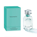 A product image featuring a Tiffany & Co. eau de parfum bottle with a clear, faceted design and a accompanying blue box, both with the brand's logo.